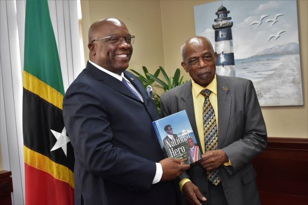 SIR KENNEDY SIMMONDS PRESENTS AUTOGRAPHED COPY OF HIS AUTOBIOGRAPHY TO PRIME MINISTER HARRIS